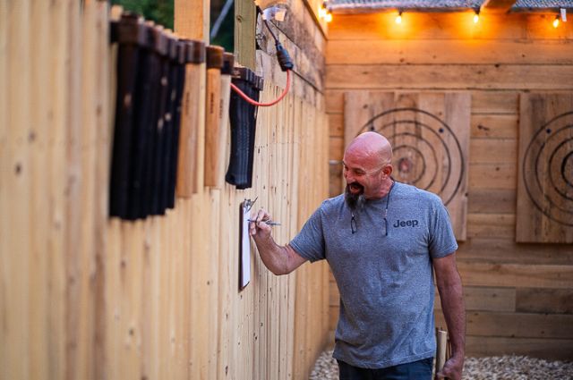 man writing score for axe throwing